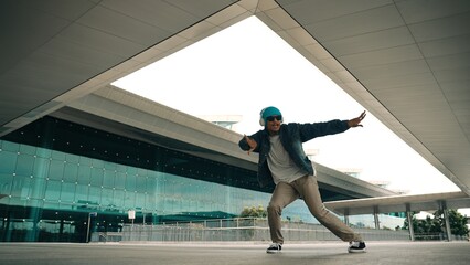 Motion shot of happy hipster practice b boy dance with stylish cloth at building. Dancer enjoy show footstep performance. Modern lifestyle, break dancing. Slow motion. Outdoor sport 2024. Sprightly.