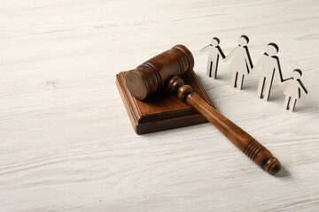 Law concept. Gavel and figures of parents with children on white wooden table, space for text