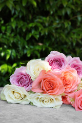 Beautiful bouquet of roses on light grey table outdoors, closeup
