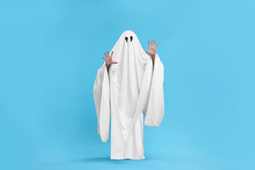 Woman in white ghost costume on light blue background. Halloween celebration