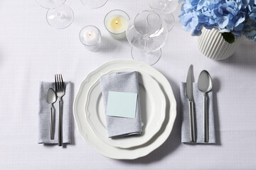 Beautiful table setting with blank card and floral decor, flat lay