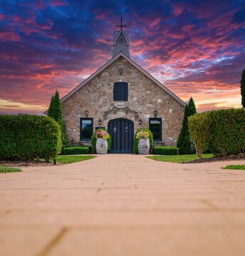 Old stone church built in 1857 with wine barrels decorated with flowers, at sunset, low angle view
