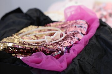 Headbands and stylish pink carnival costume with sequins in black box, closeup