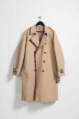 Hanger with beige trench coat on white wall