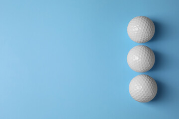 Three golf balls on light blue background, flat lay. Space for text