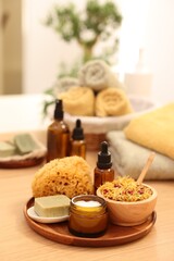 Dry flowers, loofah, soap bar, bottle of essential oil and jar with cream on wooden table indoors, space for text. Spa time