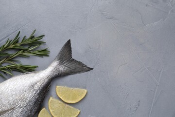 Fresh raw dorado fish, lemon and rosemary on grey table, flat lay. Space for text