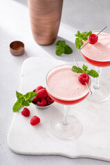 Raspberry martini in coupe glasses garnished with fresh raspberries and mint