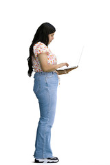 A woman, on a white background, in full height, uses a laptop, profile