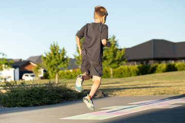 A boy is playing hopscotch on the asphalt in the playground. Active leisure for children. 