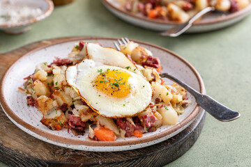 Corned beef hash with potatoes and carrots with fried egg on top