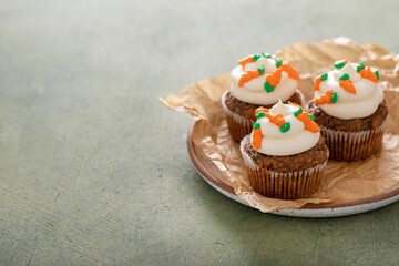 Carrot cake cupcakes with cream cheese frosting decorated with little carrots