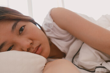 Fototapeta premium Close up of lazy Asian woman just wake up but not going to get up from the bed.