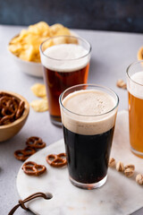 Dark stout, lager and ale beer in tall glasses on the table with snacks