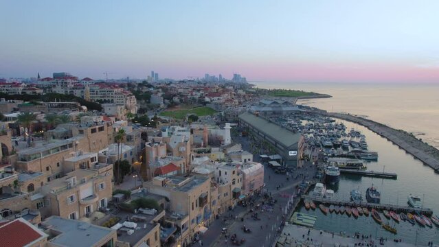 Old city of Jaffa and Jaffa port at sunset with lots of families visiting restaurants, shops and bars in the port - parallax drone shot