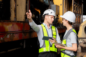 Young caucasian engineer man and woman checking train with tablet in station, team engineer inspect system transport, technician examining infrastructure, transportation and industry.