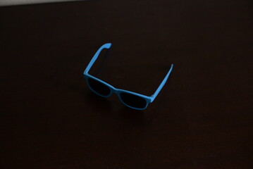 Óculos escuro azul em cima da mesa do quarto aberto