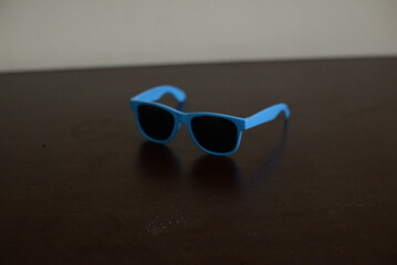 Óculos escuro azul em cima da mesa do quarto aberto