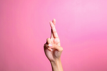 Hand with crossed fingers for luck, isolated on pink background. Hand gesture