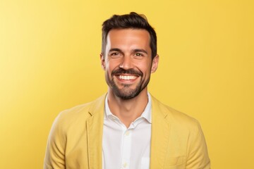 Portrait of a happy young man smiling and looking at camera on yellow background