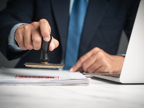 Businessman stamped for rejected documents while sitting at a desk in the office.
