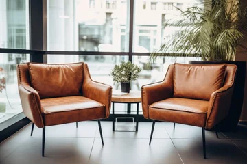 Deurstickers Two leather armchairs positioned near a coffee table in an upscale office or trendy apartment Open book agenda or planner in a meeting room at a commercial bui © The Big L