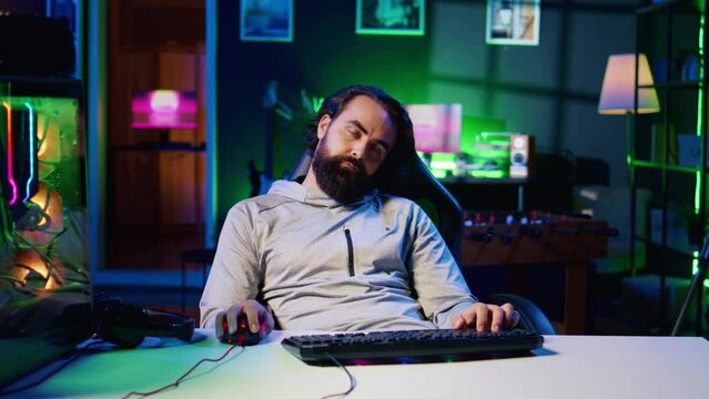 Man obsessed with playing videogames all day falling asleep at computer desk, crushing on floor from tiredness. Gamer suffering from gaming addiction feeling extremely sleepy, dropping from chair