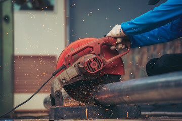 Obraz premium Construction Worker hands using Welding machinery iron metal sparking. Men hands wear protective glove Hot flame metal work cutting fire iron workshop. Locksmith use Welding machine cut metal process