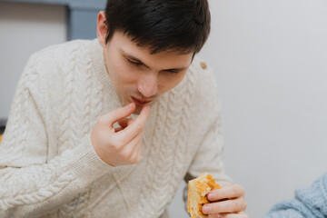 A young guy takes a surprise from a royal biscuit out of his mouth.