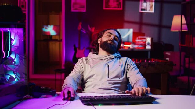 Lazy man binging videogames at home all day, feeling lifeless and disconnected from reality, mentally struggling. Sedentary gamer doing game marathon in apartment, feeling lethargic and drowsy