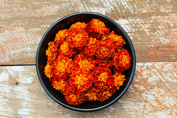 Red marigold flowers in a plate on wooden background top view 