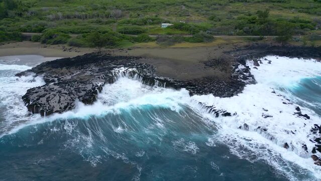 Coast and waves on volcanic rocks on a black sand beach at Reunion Island