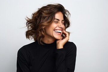 Portrait of a beautiful happy young woman laughing on a gray background