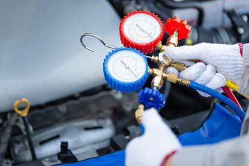 Close-up of Technician man holding monitor tool to check and fix car air conditioner system,...