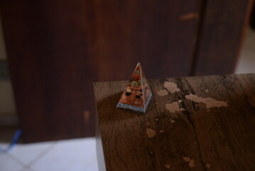 Pirâmide como peso de papel translucida em cima da mesa de madeira