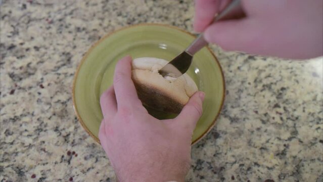 Overhead view of hands cutting an English muffin in half to be toasted for a healthy and nutritious breakfast