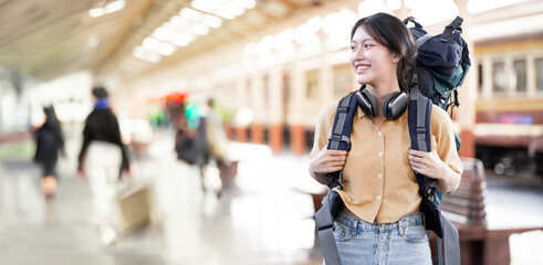 Young woman traveler with backpack waiting for train, Asian backpacker on railway platform at train...