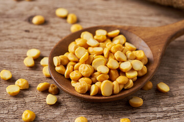 pile of split bengal gram or chana dal in wood spoon on wood table rustic food background