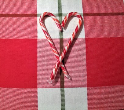 Candy cane hearts on red and white laid background