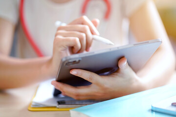 Closeup and crop hands of medical young female student in casual cloth make a short note on tablet....