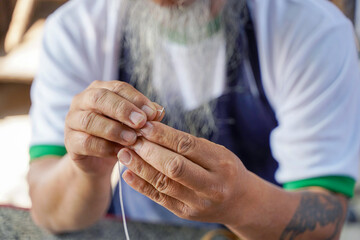 Closeup hands of Asian leather craftsman is carefully to sew a leather belt for a customer.,...