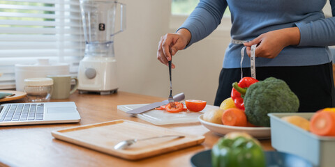 Young woman asian measure her waist in the kitchen the with vegetables and fruits. Concept of...