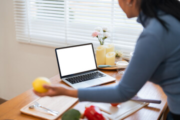 Cheerful Fat woman cooking in kitchen showing laptop mock up blank white screen in home