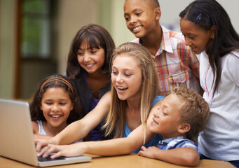 Children, typing on computer and learning in classroom for education, teaching and website information or group project. Happy diversity kids, students and girl with leadership on laptop at school