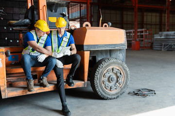 Two man engineer worker sitting on forklift check stock stainless inspecting in storage logistic factory.