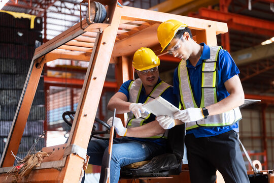 Worker wearing safety uniform drive forklift move product iron metal on shelves in warehouse. Two man engineer worker check stock stainless inspecting in storage logistic factory. - Powered by Adobe