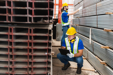 Worker wearing safety uniform using digital tablet inspect product iron metal on shelves in warehouse. Two man engineer worker check stock stainless inspecting in storage logistic factory.