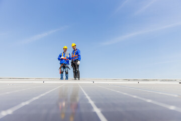 Technicians are installing and inspecting standards of solar panels on roof of an industrial...