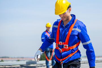 Technicians are installing and inspecting standards of solar panels on roof of an industrial...