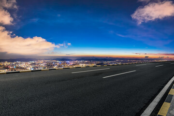 Asphalt road and city skyline with sky clouds at night. High Angle view.